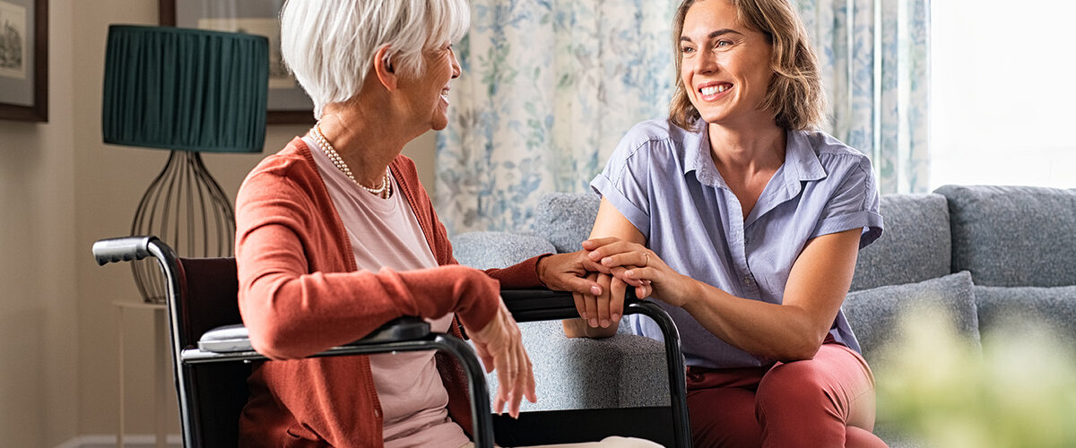 Seniorin im Rollstuhl, Pflegerin hält ihre Hand