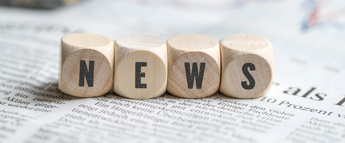 Schriftzug NEWS aus Holzwürfeln auf Zeitung