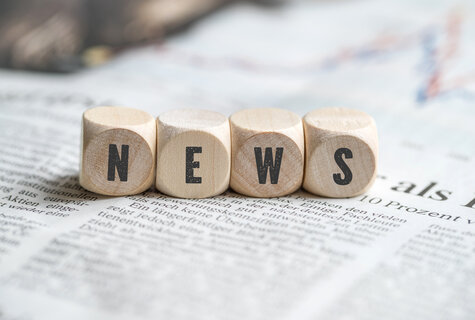 Schriftzug NEWS aus Holzwürfeln auf Zeitung
